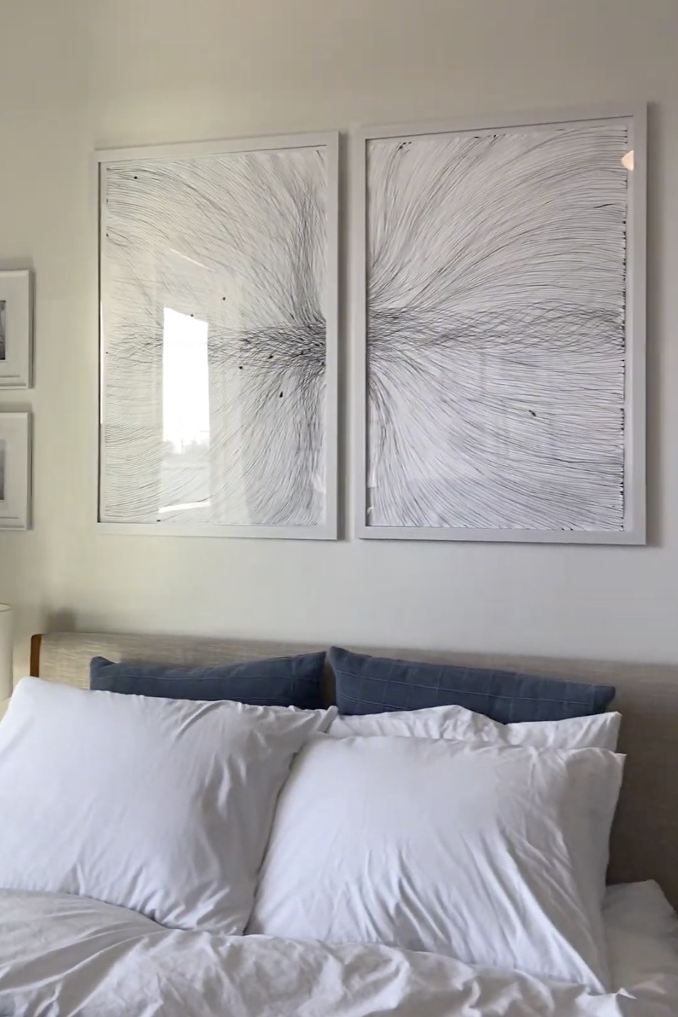 Two large framed line drawings hanging side by side above a bed, each nearly as wide as a pillow is long.