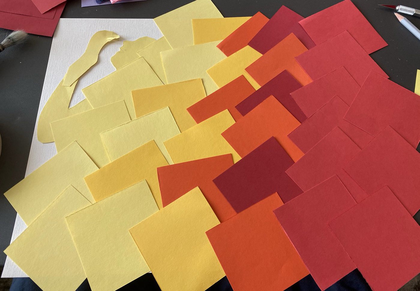 Collage of overlapping paper squares stepping from pale yellow at the left through orange to deep red at the right.